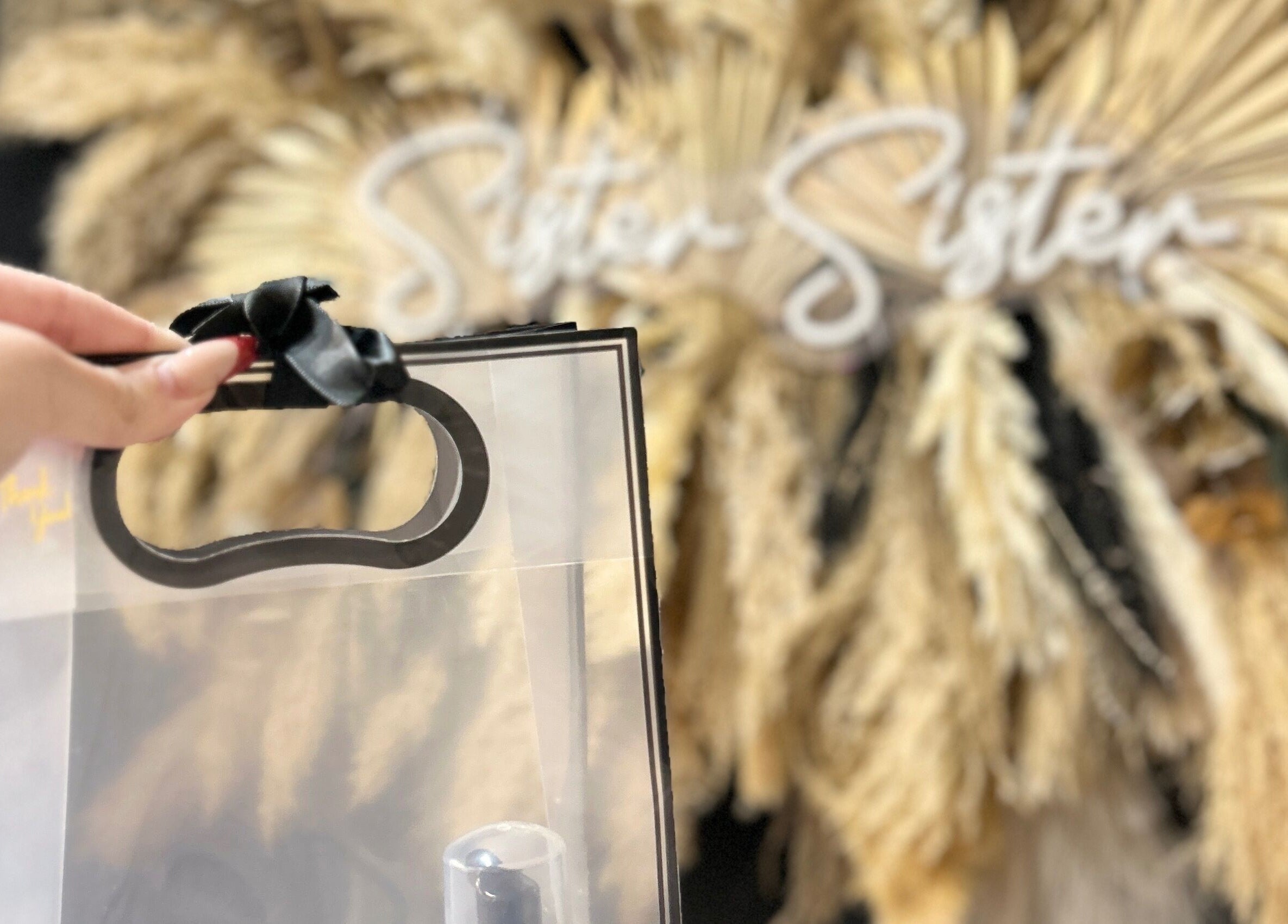 Transparent gift bag with black handle and bow at JMBeauty, Brayton, England, GB.