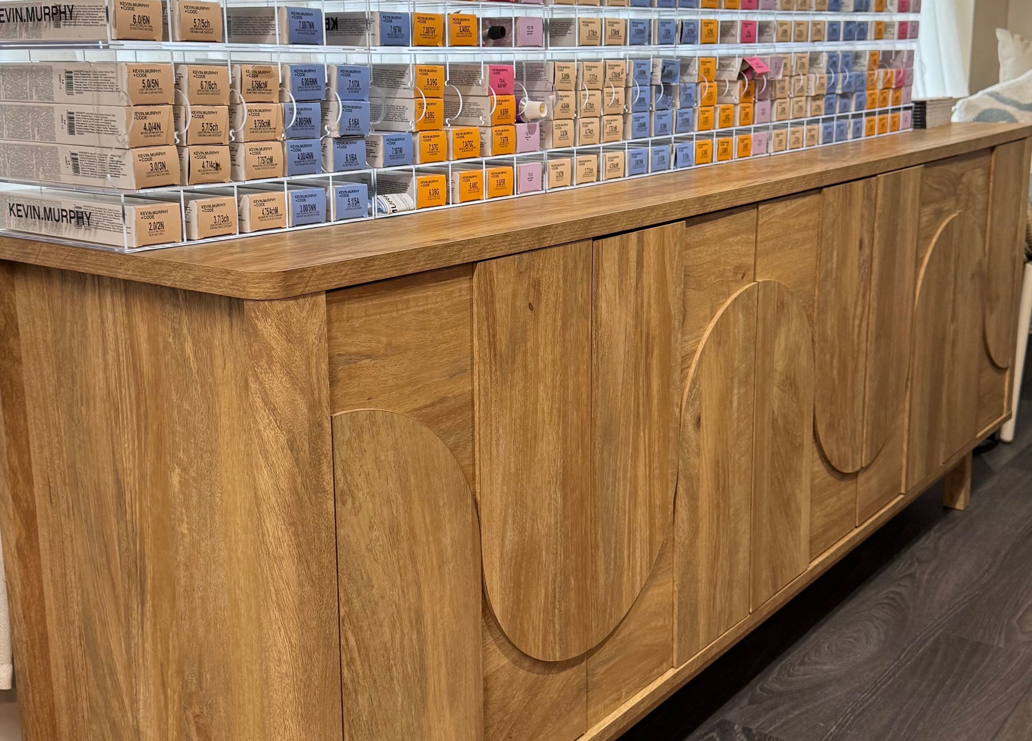 Handcrafted wooden cabinet with hair products at South Beach Salon, Helston, England, GB.