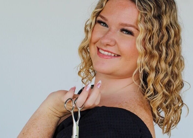 Hair stylist smiling with scissors at Beauty By Corbyn, Boiling Springs, South Carolina, US.