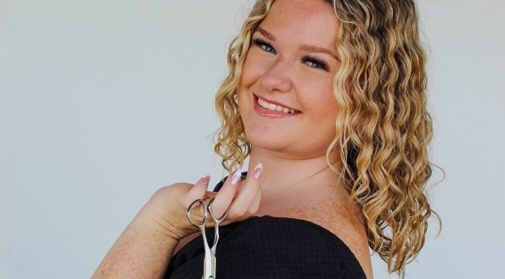 Hair stylist smiling with scissors at Beauty By Corbyn, Boiling Springs, South Carolina, US.