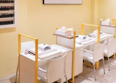 Modern nail salon at Pomegranate, Cape Town, Western Cape, ZA, featuring sleek white stations and polish display.