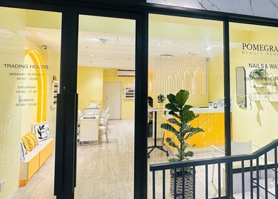 Front view of Pomegranate, a beauty venue in Cape Town, Western Cape, ZA with bright yellow interior and plant decor.