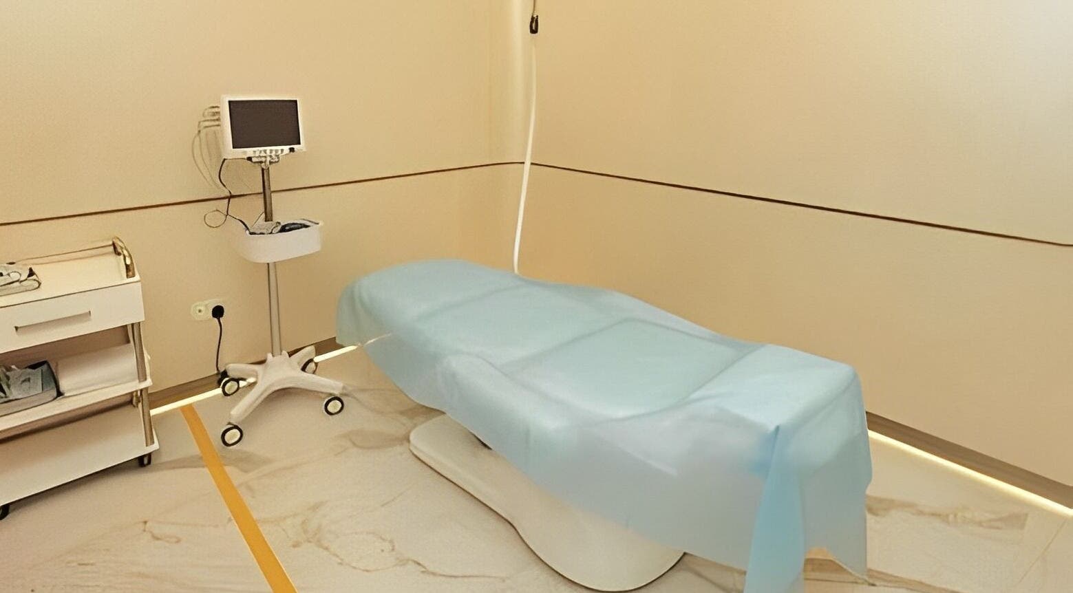 Modern treatment room at Reborn Clinic, Dubai, Dubai, AE, featuring a blue-covered medical bed and equipment.