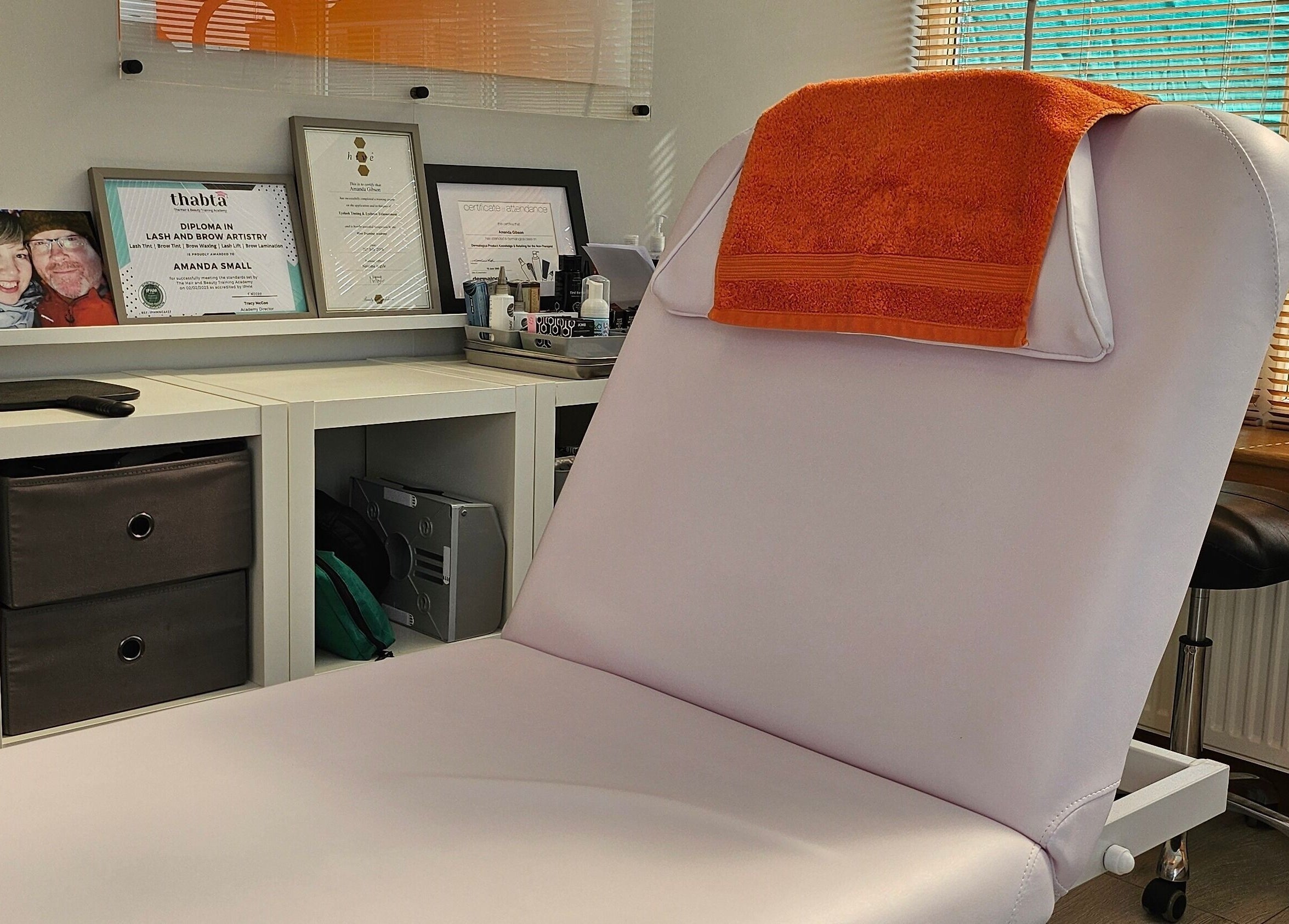 Cozy treatment room at Brow Wow and Scalp Ethic, Kirkcaldy, Scotland, GB with certificates and orange towel.