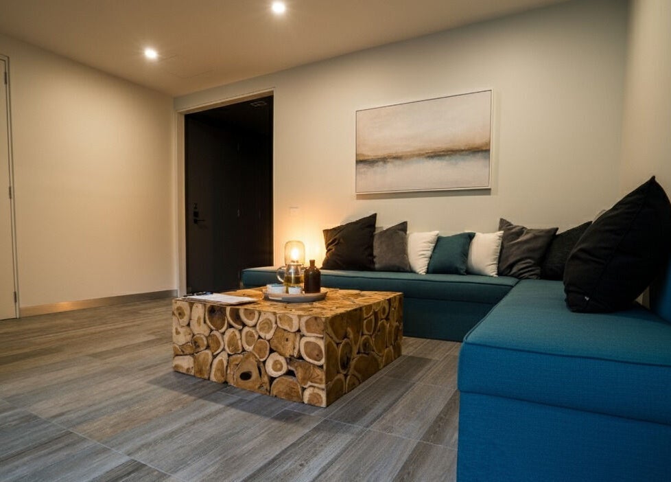 Relaxing lounge area at Innerverse Float & Wellness Southbank, Melbourne, AU featuring teal seating and a rustic table.