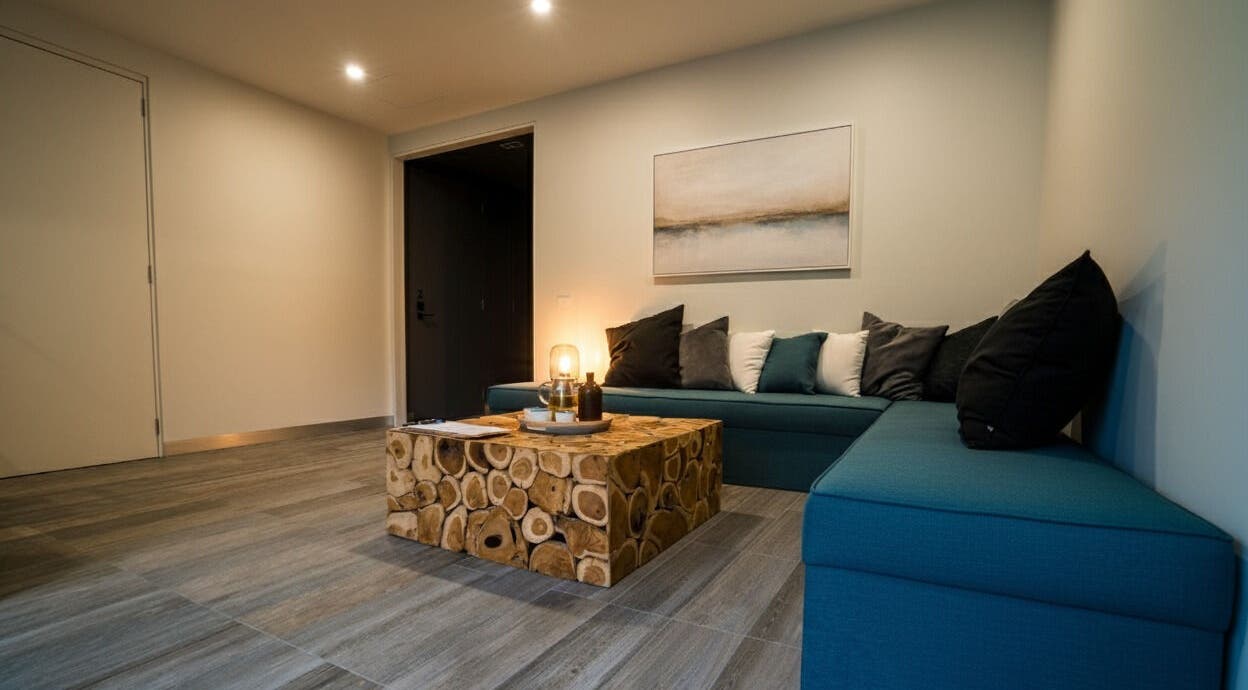 Relaxing lounge area at Innerverse Float & Wellness Southbank, Melbourne, AU featuring teal seating and a rustic table.