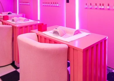 Manicure stations at Kikki & Co Beauty Bar in Cape Town, Western Cape, ZA with pink chairs and tables.