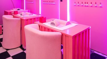 Manicure stations at Kikki & Co Beauty Bar in Cape Town, Western Cape, ZA with pink chairs and tables.