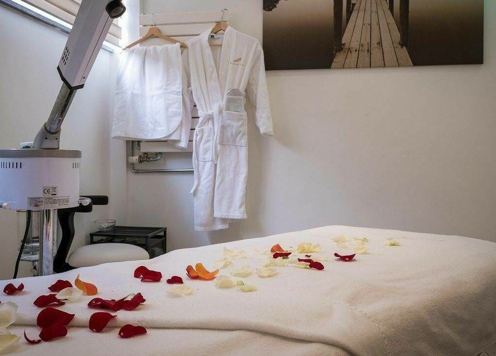 Table de massage avec pétales et peignoir à Melting Pot Louise, Sint-Gillis, Brussels Hoofdstedelijk Gewest, BE.