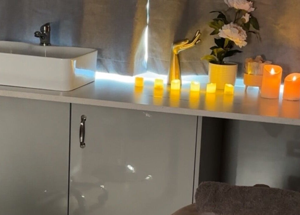 Candlelit spa ambiance at The Glow Room in York, England, GB with a modern sink and floral decor.