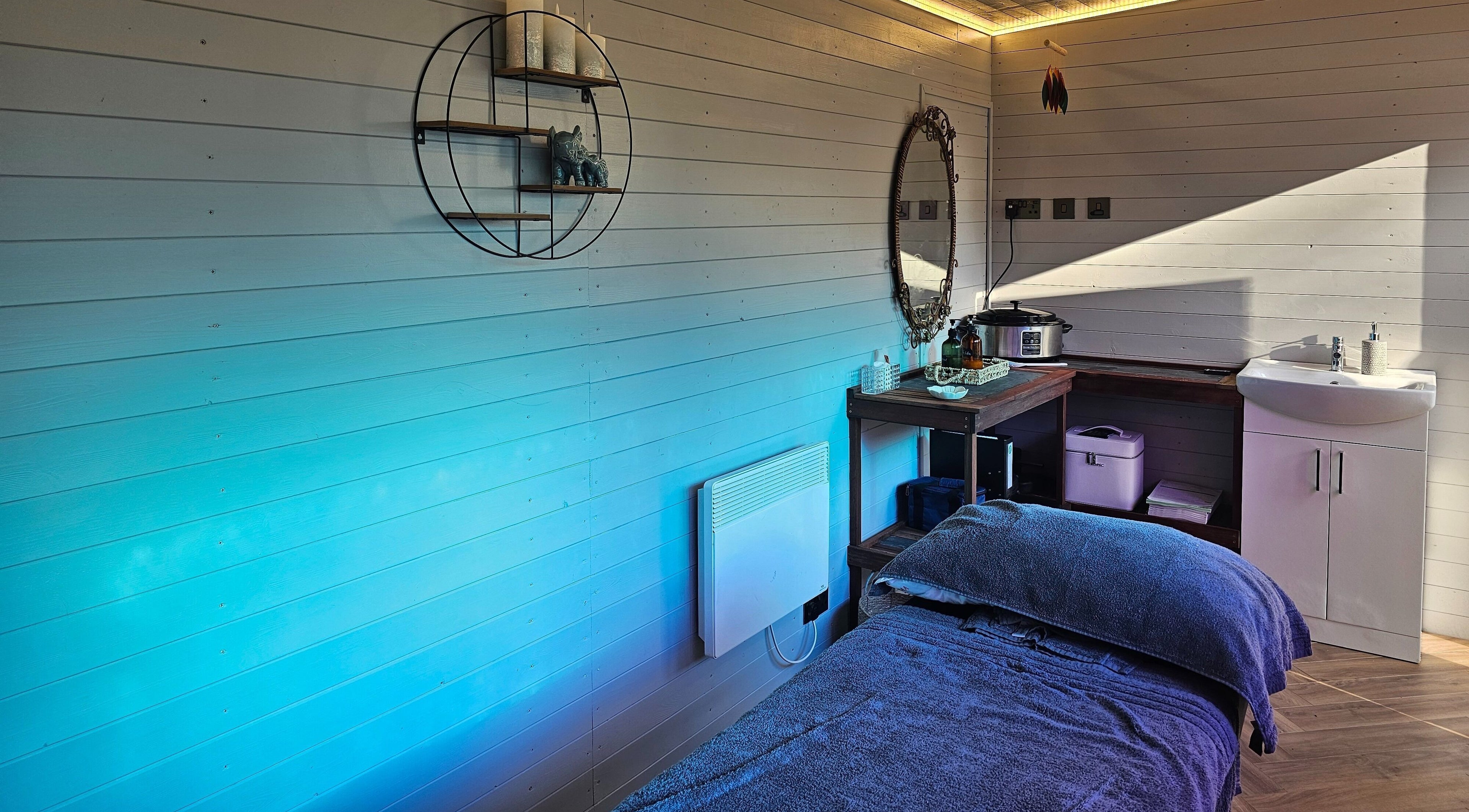 Relaxing massage room at Jem Stones Holistic Massage in Swindon, England, GB, featuring soothing blue tones.