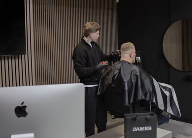 Kapper knipt klant bij James Barbershop, Spijkenisse, Zuid-holland, NL, in een strakke moderne kamer.