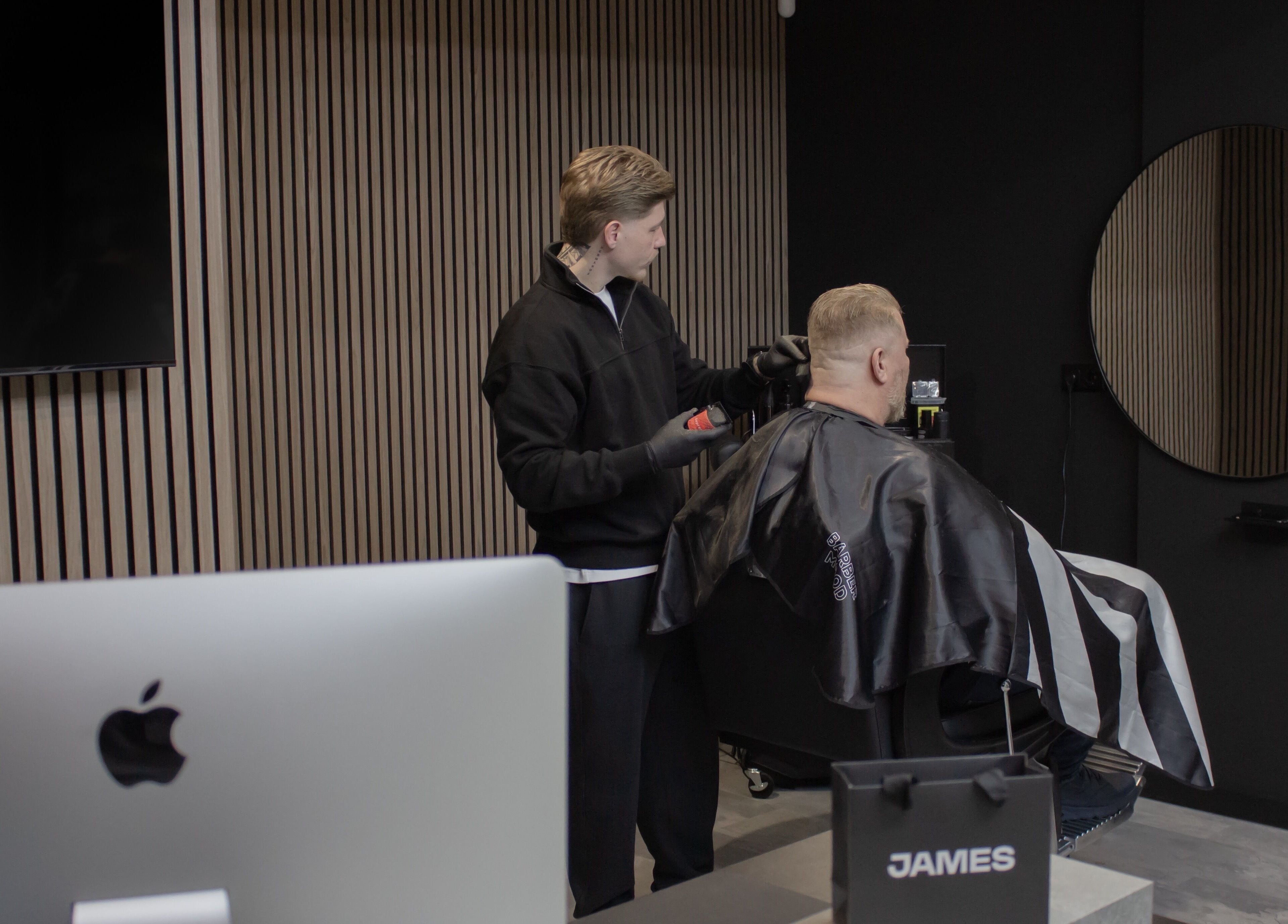 Kapper knipt klant bij James Barbershop, Spijkenisse, Zuid-holland, NL, in een strakke moderne kamer.
