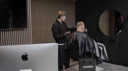 Kapper knipt klant bij James Barbershop, Spijkenisse, Zuid-holland, NL, in een strakke moderne kamer.