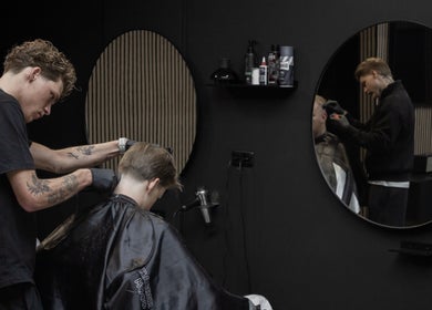 Kapper bezig met knippen bij James Barbershop, Spijkenisse, Zuid-Holland, NL.