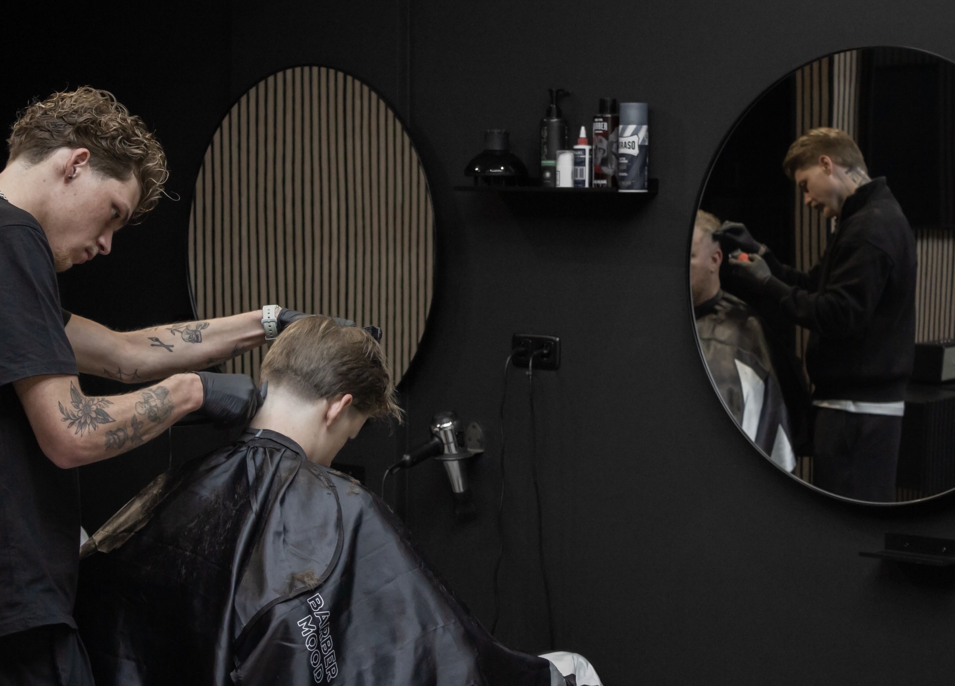 Kapper bezig met knippen bij James Barbershop, Spijkenisse, Zuid-Holland, NL.