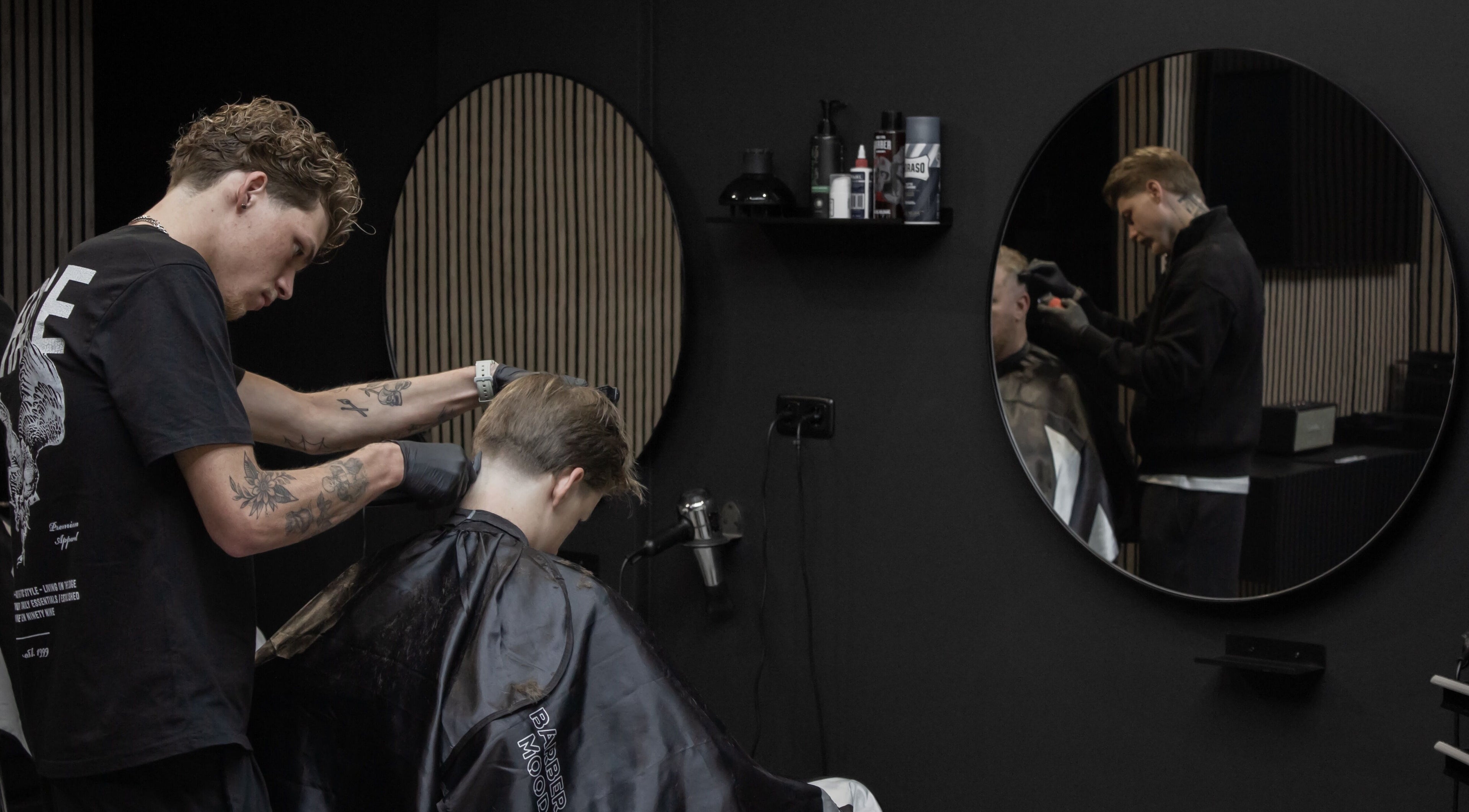 Kapper bezig met knippen bij James Barbershop, Spijkenisse, Zuid-Holland, NL.