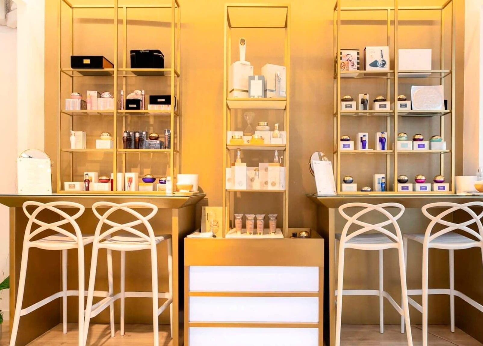 Estantería dorada con productos de belleza en Premier Sitges, Sitges, Catalunya, ES. Un ambiente elegante y moderno.