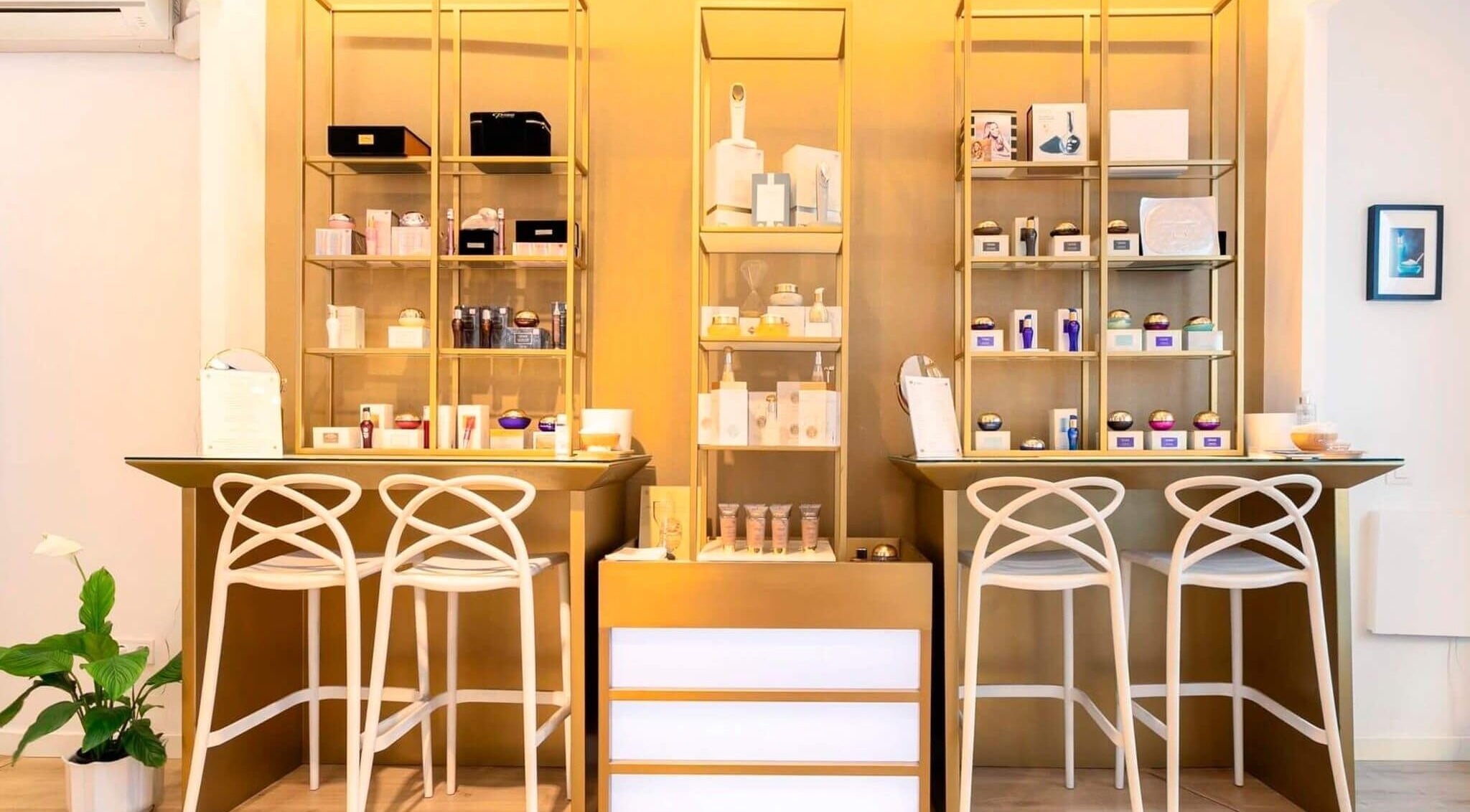 Estantería dorada con productos de belleza en Premier Sitges, Sitges, Catalunya, ES. Un ambiente elegante y moderno.