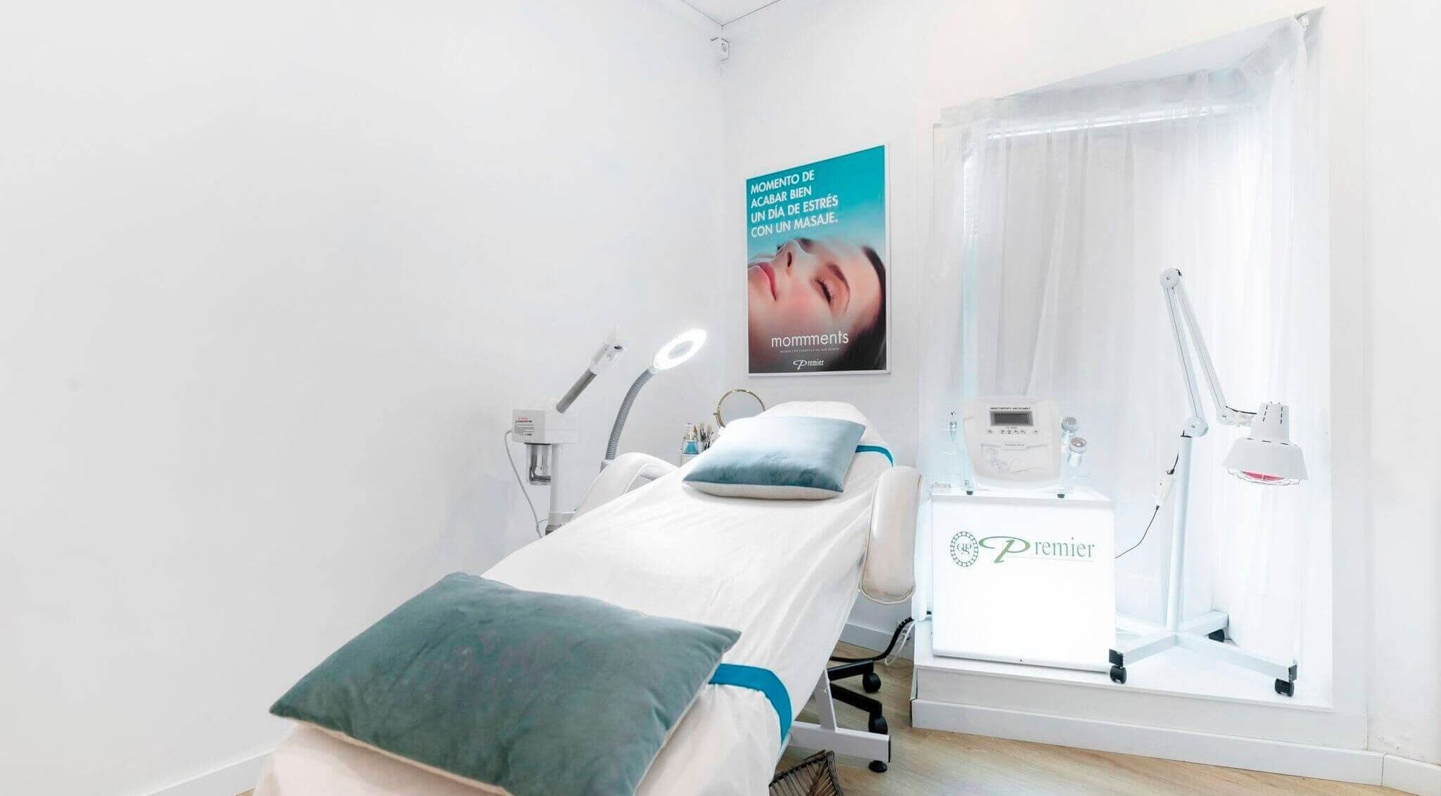 Sala de tratamientos en Premier Sitges, Sitges, Catalunya, ES con cama y equipo estético iluminado.