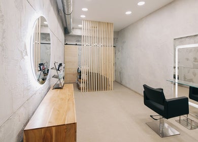 Interior moderno de DIM Salón - Peluquería Malasaña en Madrid, Comunidad De Madrid, ES con silla y espejo iluminado.