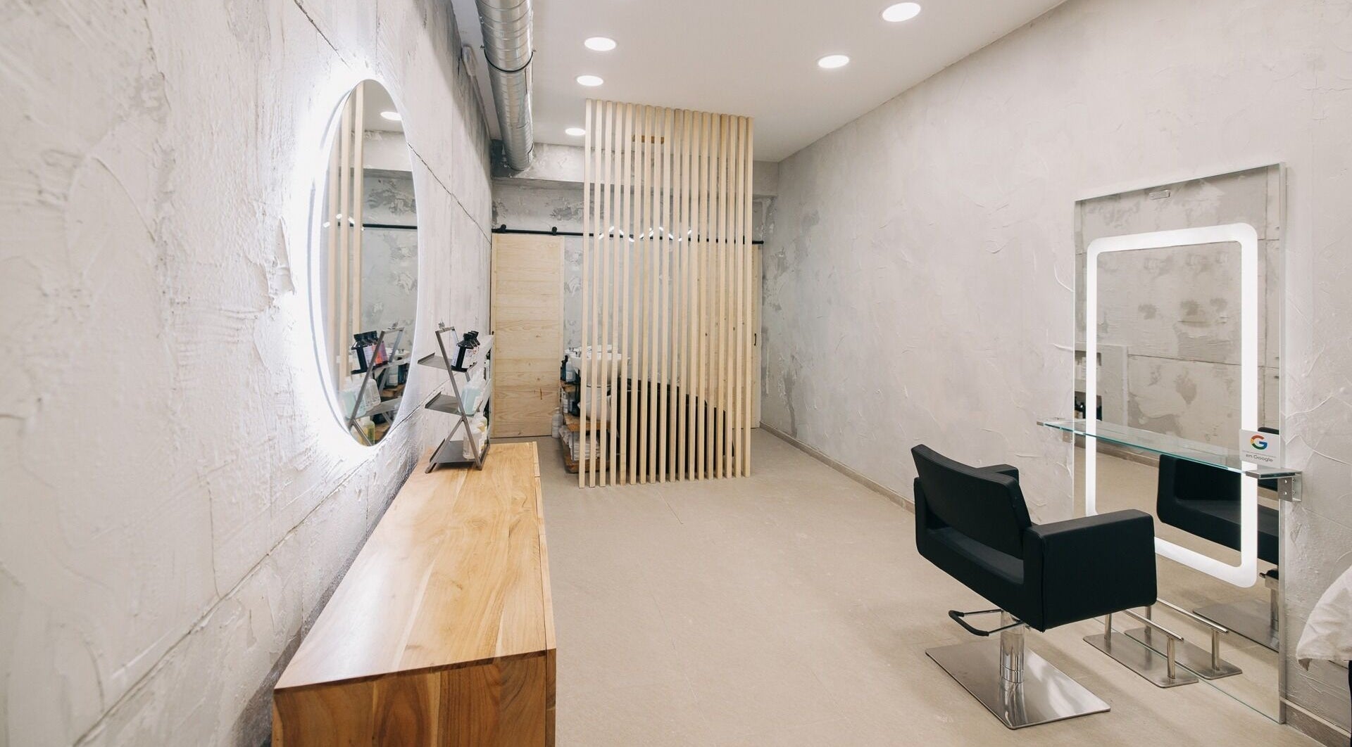 Interior moderno de DIM Salón - Peluquería Malasaña en Madrid, Comunidad De Madrid, ES con silla y espejo iluminado.