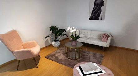 Sala de espera elegante en Friseurstudio by Lourdes Betancourt, Berlín, Berlín, DE con sillón rosa y sofá blanco.