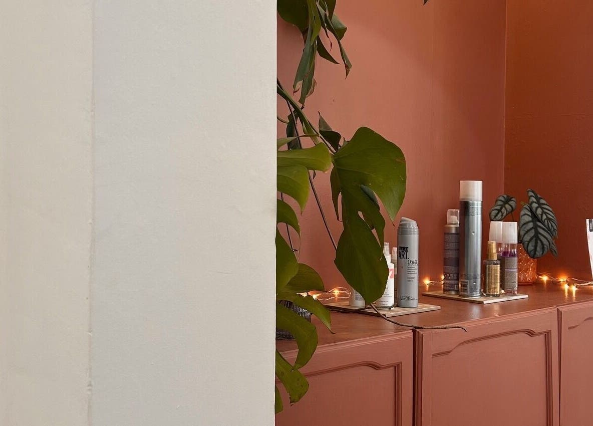 Elegant beauty products on a wooden shelf at Mantra Studio, Leeds, England, GB, with green leaves and warm lighting.