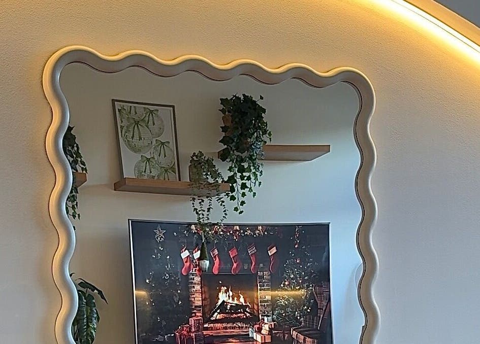 Elegant wavy mirror at The Pixie Studio, Cardiff, Wales, GB. Quirky decor with plants and wall art.