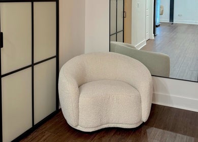 Elegant corner at Brand & Co., Philadelphia, Pennsylvania, US, featuring a soft, white chair and large mirror.