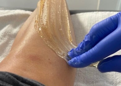 Sugaring treatment at The Sugar Room Okotoks, Alberta, CA, showcasing smooth application on a leg.