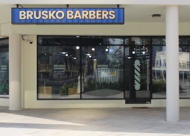 Exterior of Brusko Barbers in دبي, دبي, AE, showcasing modern glass facade and signage.