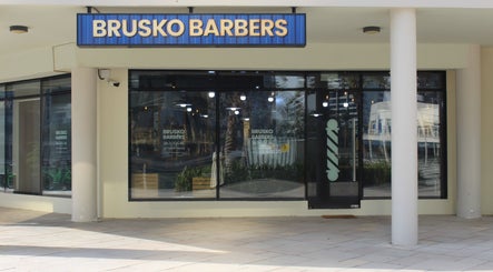 Exterior of Brusko Barbers in دبي, دبي, AE, showcasing modern glass facade and signage.