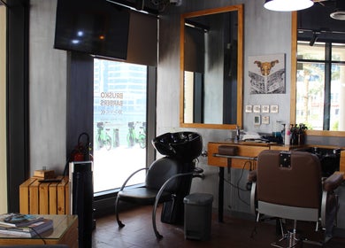 Modern interior of Brusko Barbers in دبي, دبي, AE, featuring stylish chairs and wooden mirrors.