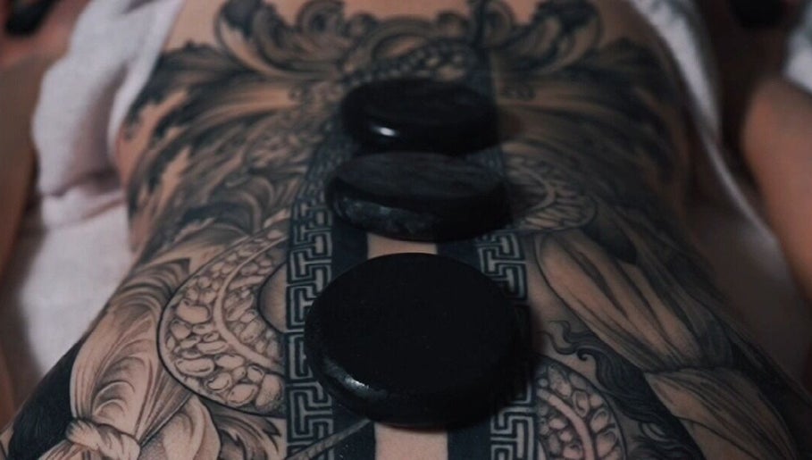 Hot stone massage on tattooed back at Nurvana Studio, Melbourne, Victoria, AU.