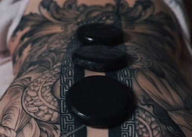 Hot stone massage on tattooed back at Nurvana Studio, Melbourne, Victoria, AU.