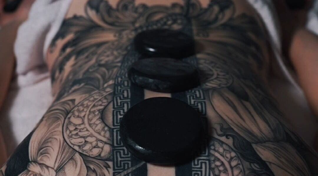 Hot stone massage on tattooed back at Nurvana Studio, Melbourne, Victoria, AU.
