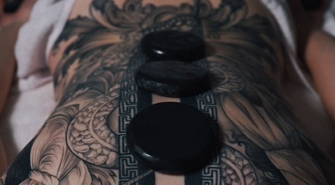 Hot stone massage on tattooed back at Nurvana Studio, Melbourne, Victoria, AU.