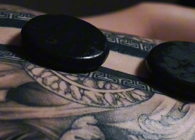 Hot stones on tattooed skin at Nurvana Studio, Melbourne, Victoria, AU for soothing therapy.