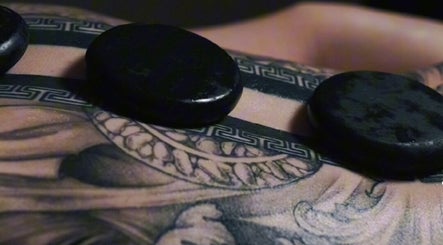 Hot stones on tattooed skin at Nurvana Studio, Melbourne, Victoria, AU for soothing therapy.