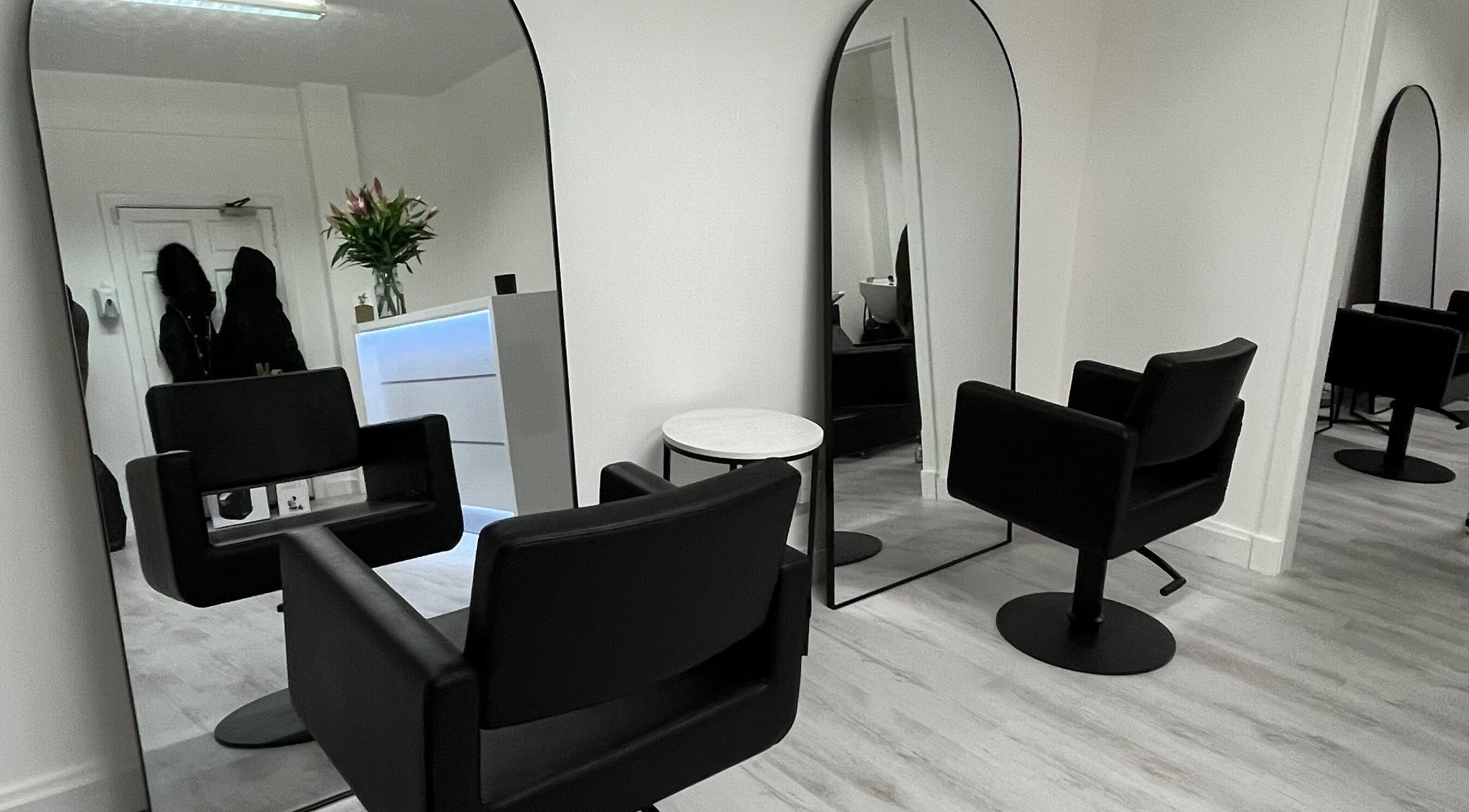 Chic interior of Hair by Alex Blair in Haddington, Scotland, GB featuring sleek black chairs and large mirrors.