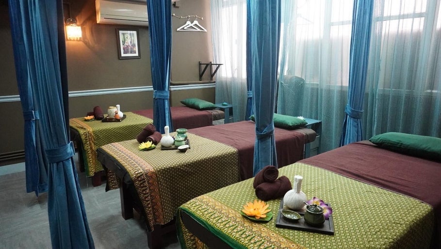 Tranquil massage beds at Siam Thai Massage & Spa, HK, HK, surrounded by calming curtains and warm lighting.