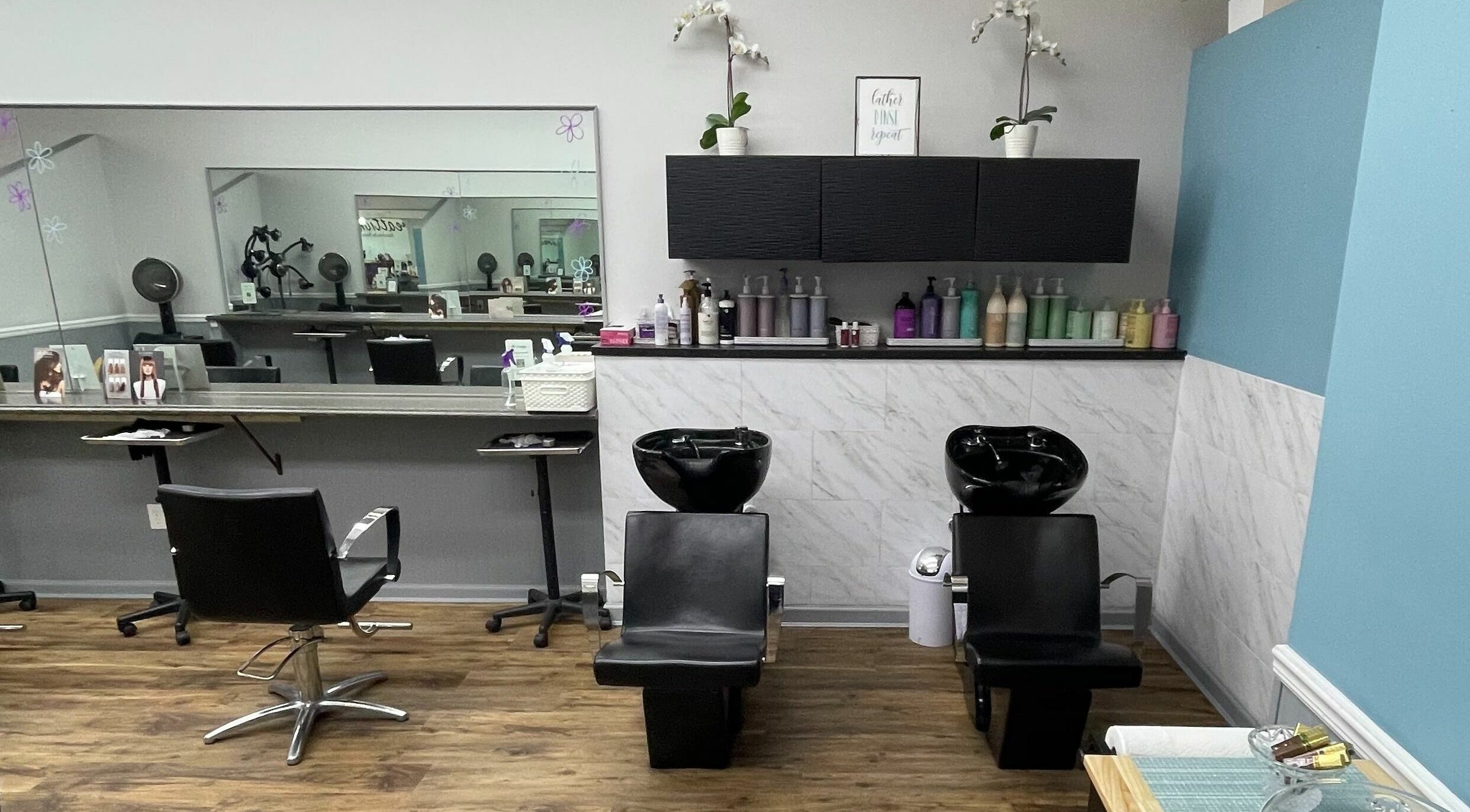 Modern salon interior of Hair Creations in Ronkonkoma, New York, US with sleek styling stations and wash basins.