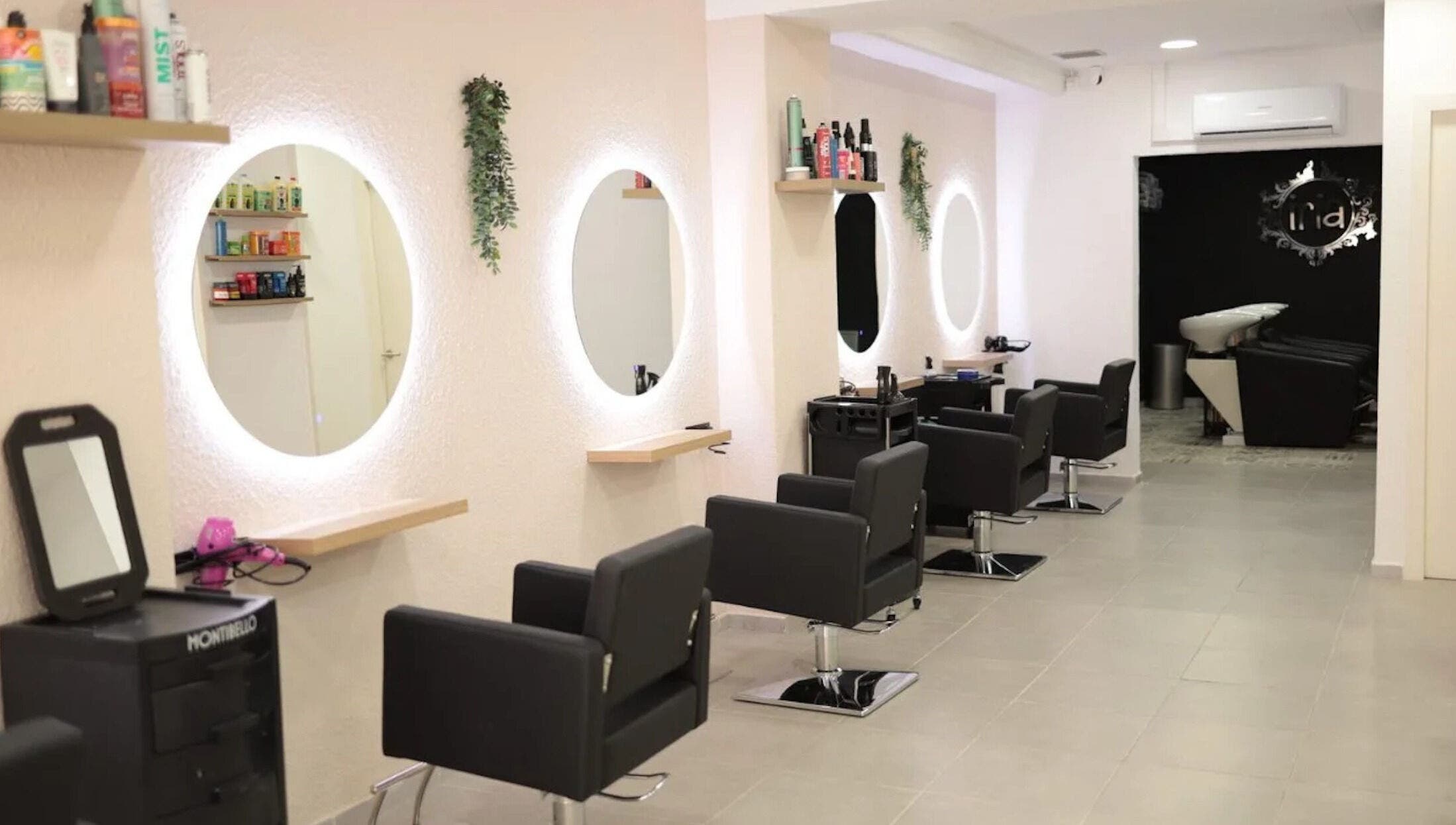 Elegante interior de Iria Perruquers en Cubelles, Catalunya, ES, con sillas negras y espejos iluminados.