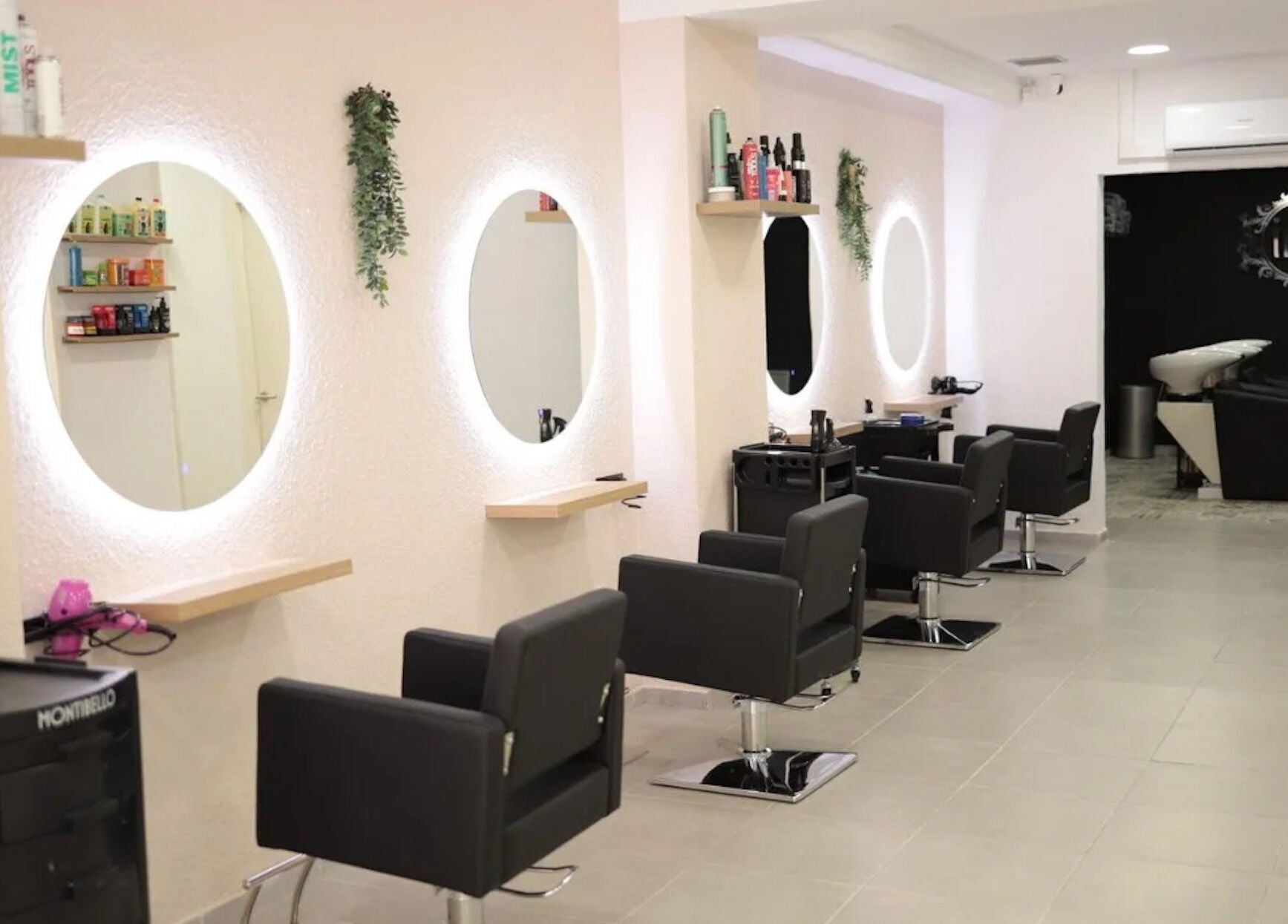 Elegante interior de Iria Perruquers en Cubelles, Catalunya, ES, con sillas negras y espejos iluminados.