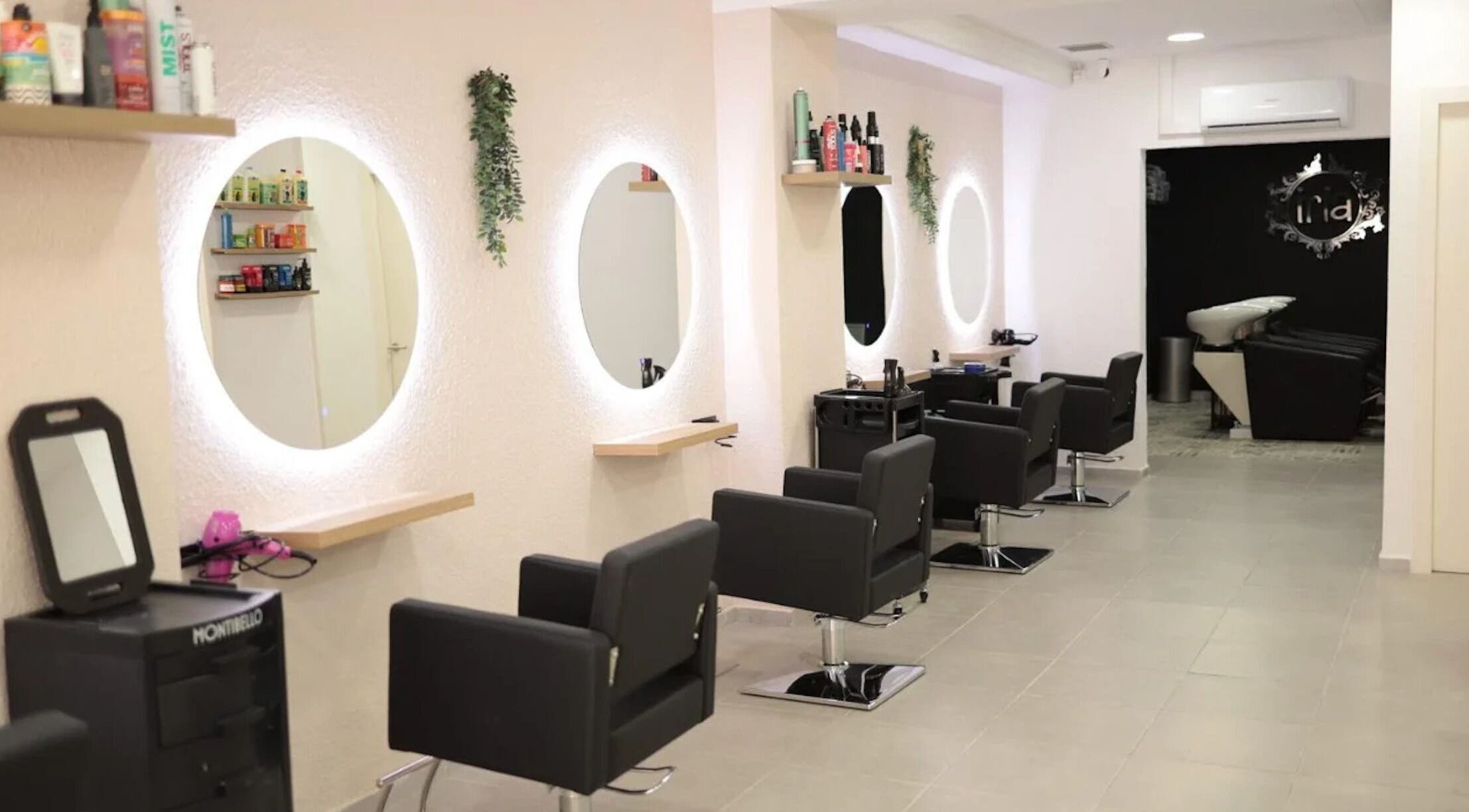 Elegante interior de Iria Perruquers en Cubelles, Catalunya, ES, con sillas negras y espejos iluminados.