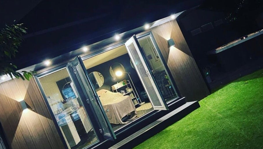 Cozy wellness room at Elevè Skin Clinic, Radcliffe, England, GB, illuminated at night with open glass doors.