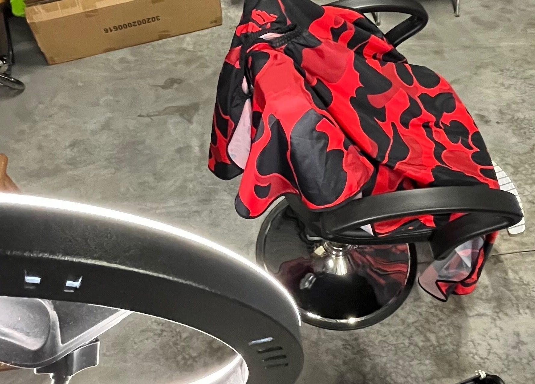 Espace moderne chez Tms Cutz à Zaventem, Vlaams Gewest, BE, avec chaise de coiffure et cape rouge à motifs.