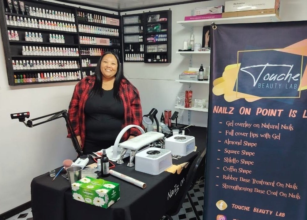 Inside Touché Beauty Lab in Cape Town, showcasing a nail technician with extensive nail polish collection.