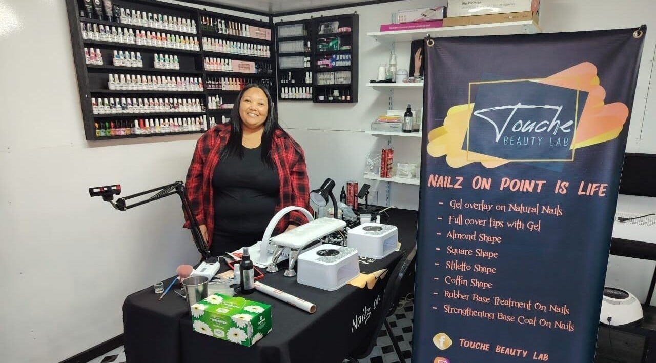 Inside Touché Beauty Lab in Cape Town, showcasing a nail technician with extensive nail polish collection.
